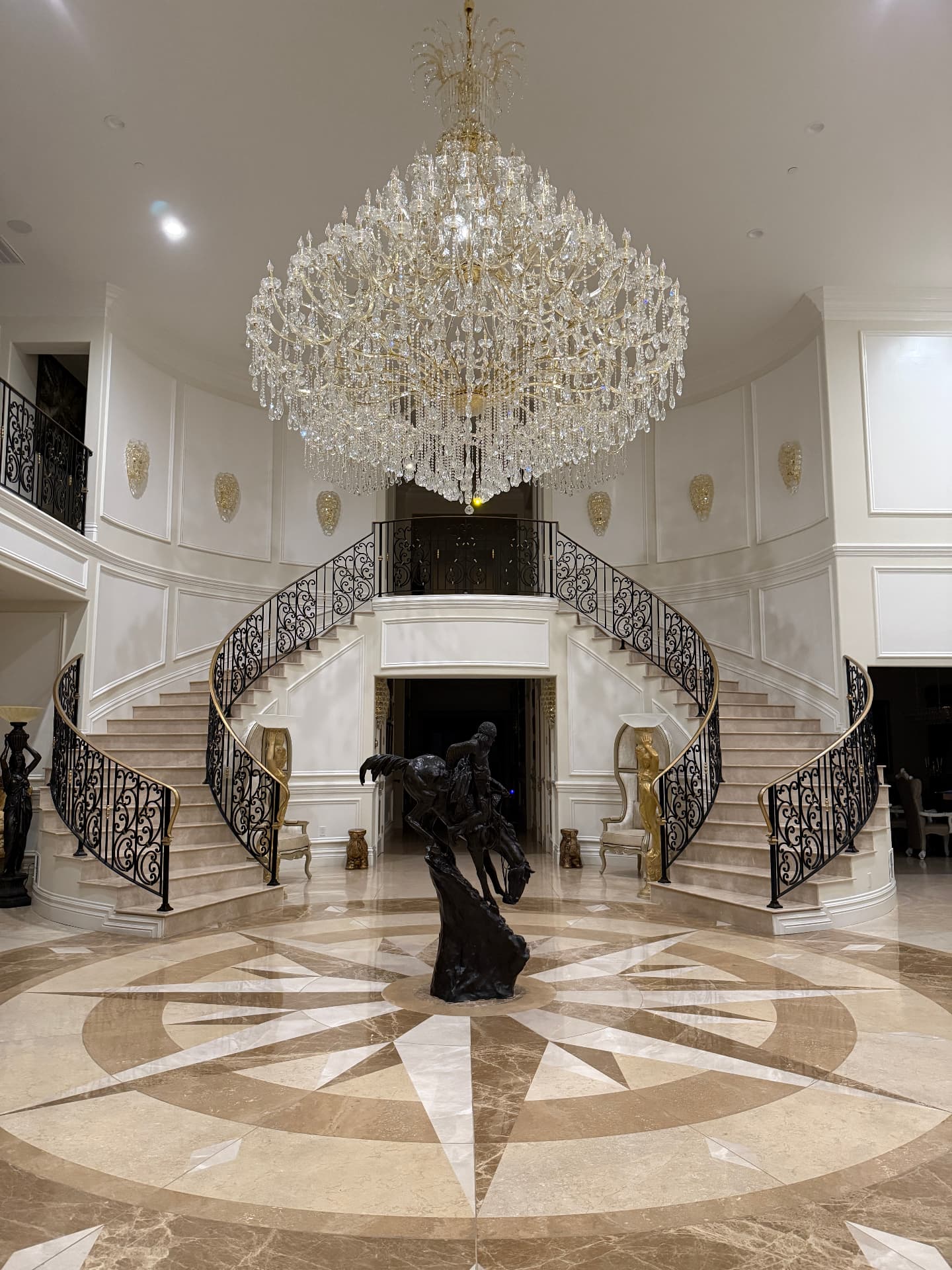 Grand foyer with polished marble floors, a sweeping staircase, and a crystal chandelier